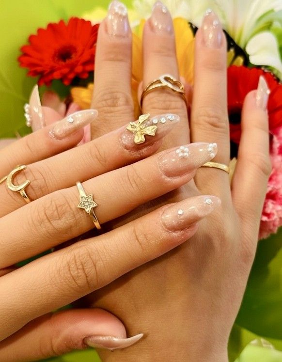 Sheer nails decorated with pearls, crystals and a gold bow